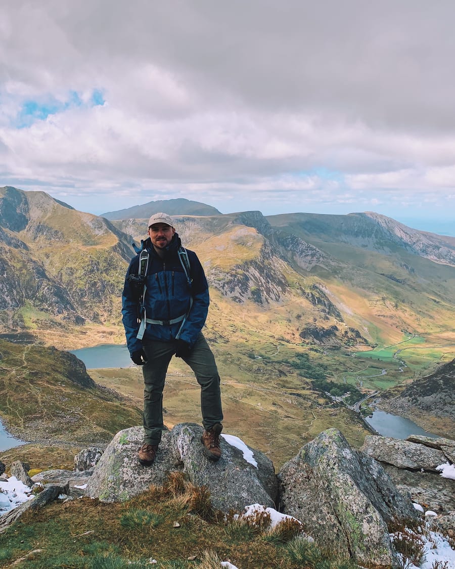 Carl on a mountain summit, valley and lakes behind him